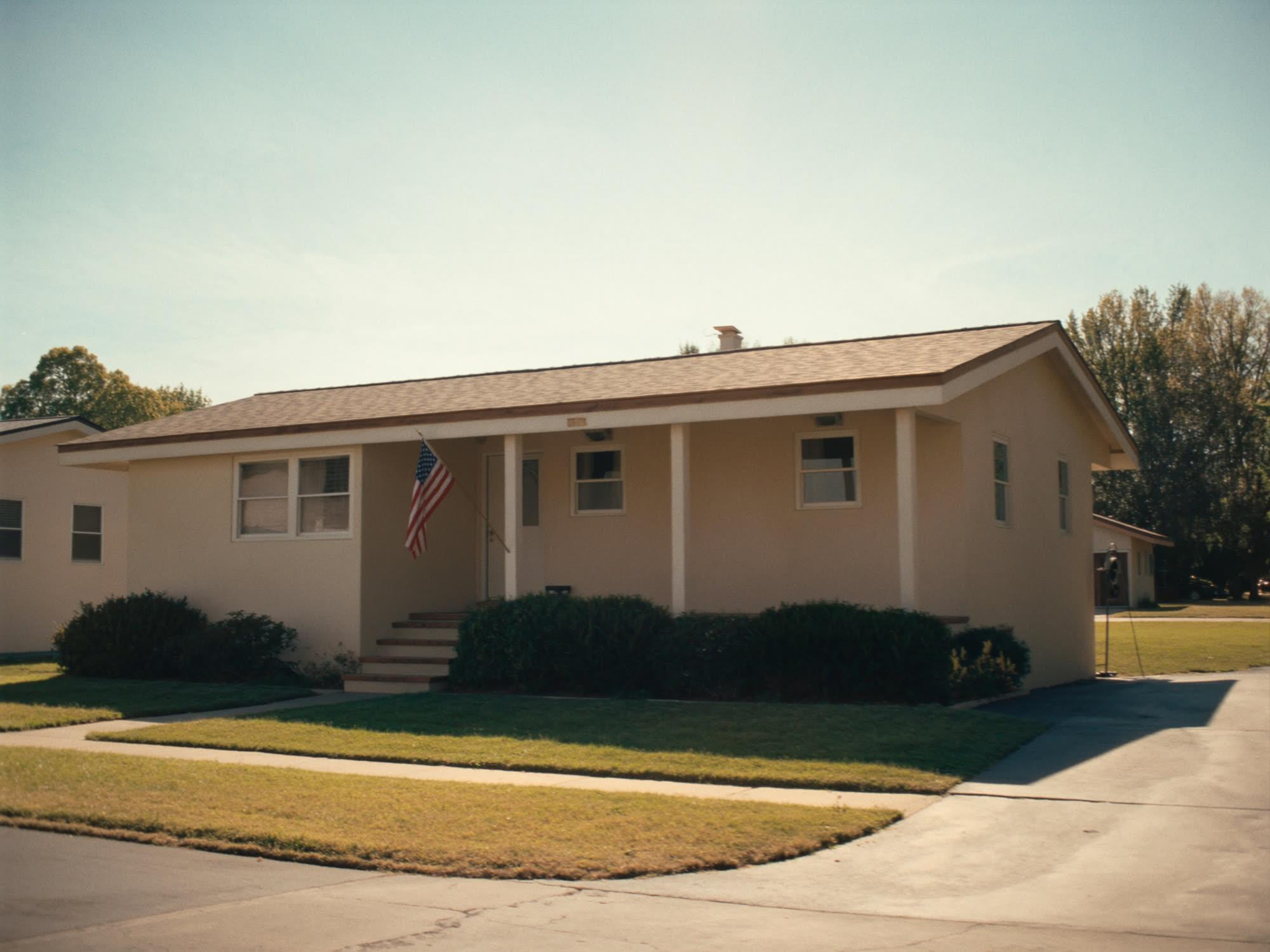 A tidy single-story home with a small American flag beside the front door.
