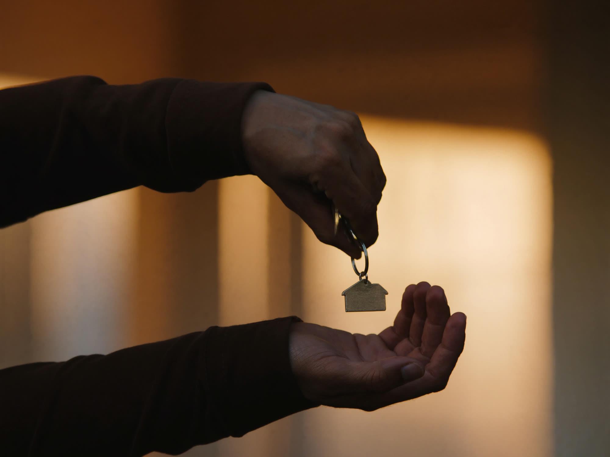 A close-up of house keys being passed from one hand to another.