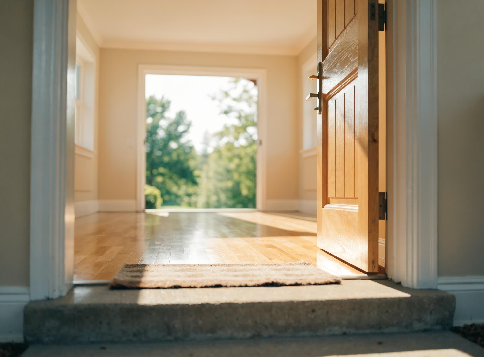 An open front door looking into a bright, freshly prepared sunlit room.